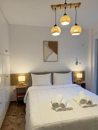 Un dormitorio con una gran cama blanca con toallas. en Boho Coastal Retreat with Jacuzzi, 1 min to Beach, en Atenas