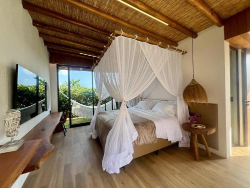 a bedroom with a canopy bed with white curtains at Umbelina Pousada Boutique in Porto De Galinhas