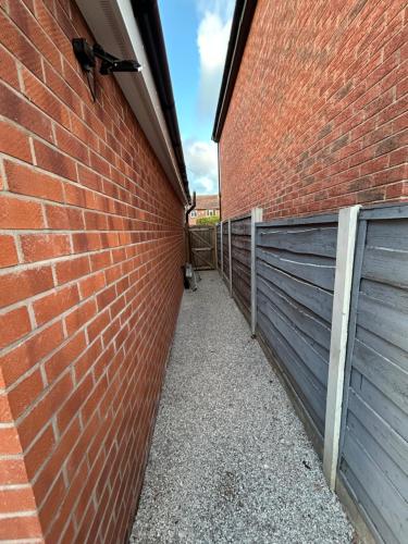 a brick wall with a gate and a fence at Cosy Corner Cheadle in Cheadle