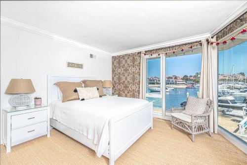 ein Schlafzimmer mit einem Bett und einem Balkon mit einem Yachthafen in der Unterkunft Iconic 4Br Bayfront Home W Unmatched Indooroutdoor Living By Beachview Rentals in Newport Beach