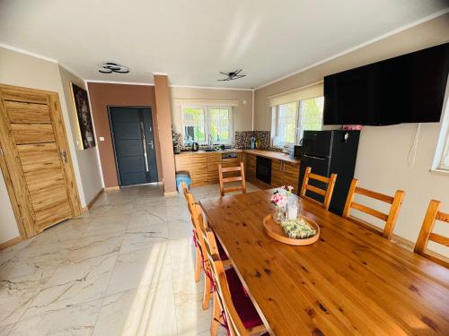 a living room with a wooden table and a kitchen at Zajazd Jędruś - Domki Całoroczne in Idzików