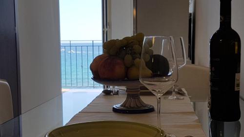 ジャルディーニ・ナクソスにあるLoft Profumo di Mareのワイングラスと一緒にテーブルに置いたフルーツボウル