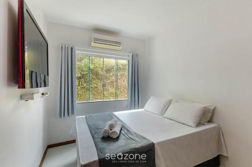 a white bedroom with a bed and a window at Apto 2 Quartos a 200 m da Praia MAO0203 in Cururupe