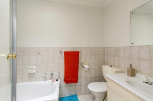 La salle de bains est pourvue de toilettes blanches et d'une serviette rouge. dans l'établissement Modern 2BR Apartment North Adelaide, à North Adelaide