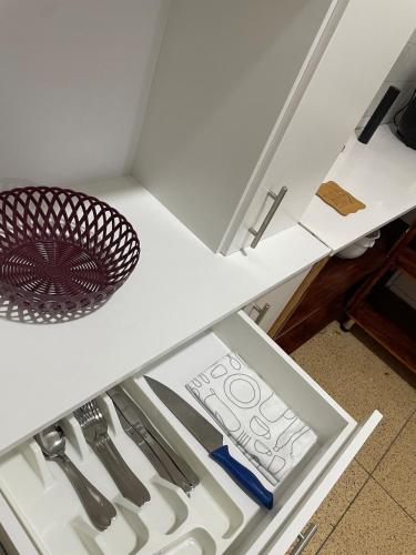 un tiroir dans un réfrigérateur blanc contenant des ustensiles dans l'établissement Lovely bedroom in a centrally located apartment, à Maputo