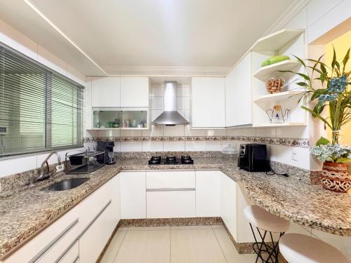 a kitchen with white cabinets and a sink at Casa moderna e extremamente confortável - R1552 in Balneário Camboriú