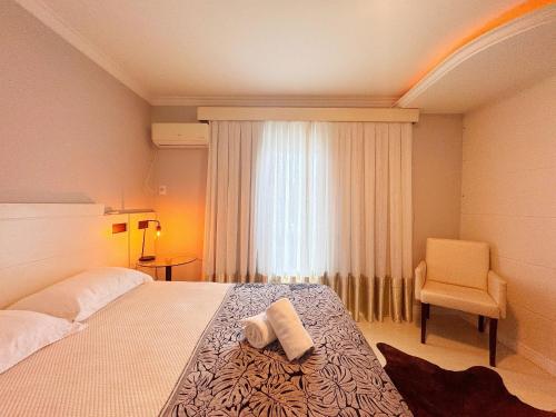 a bedroom with a bed and a chair and a window at Casa moderna e extremamente confortável - R1552 in Balneário Camboriú