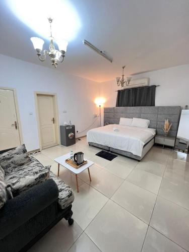 a bedroom with a bed and a couch and a table at Royale Rooms in Al Ain