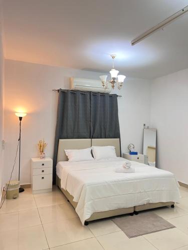 a bedroom with a white bed with a black curtain at Royale Rooms in Al Ain