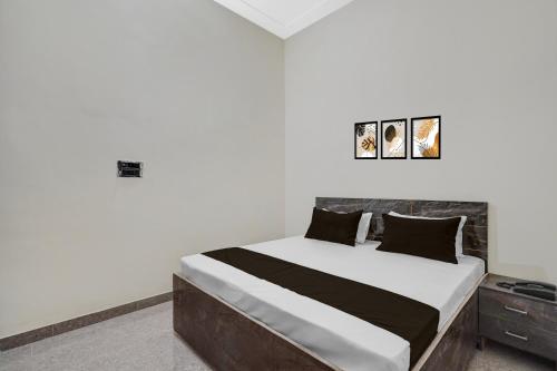 une chambre avec un lit avec des draps blancs et des oreillers noirs dans l'établissement Hotel O Choudhary Hotel and Resort, à Anūpnagar
