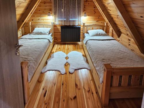 2 camas en una cabaña de madera con suelo de madera en Snowflake, en Žabljak