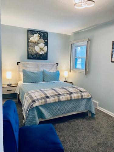 a bedroom with a bed and two blue chairs at Lake Trail Cottage in Michigan City