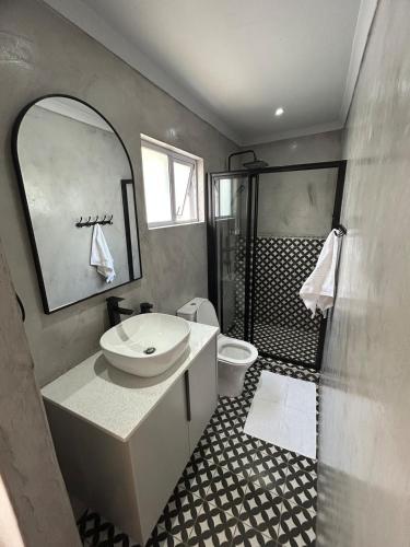 a bathroom with a sink and a toilet and a shower at Opulent Escape Secret Nest in Gqeberha
