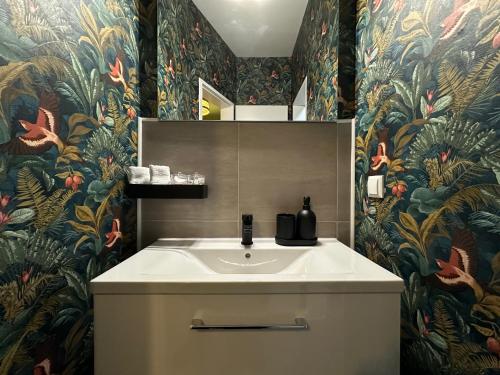 baño con lavabo y papel pintado con motivos florales en Attraktives City-Apartment No4, en Bremen