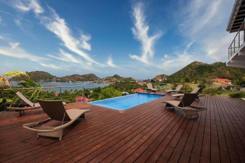 a deck with lounge chairs and a swimming pool at Villa Mangouste in Terre-de-Haut