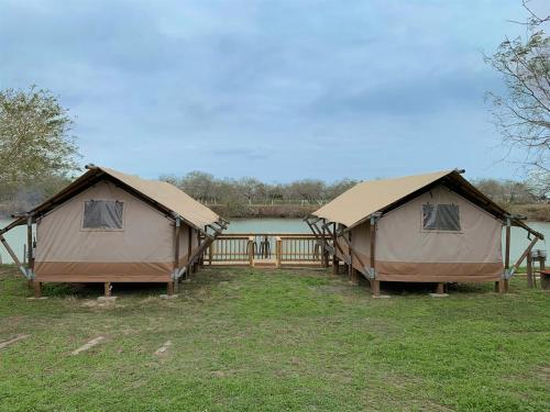 two tents in a field next to a lake at Glamping Escape Safari Tent Near SpaceX in Colonia Acres