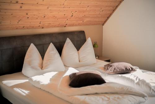 uma cama com almofadas brancas em cima em Gesundheitsbauernhof -Landhof - Offenbacher em Seckau