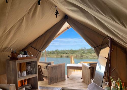 a tent with a table and a view of the water at Cozy Glamping Minutes from SpaceX Launches in Colonia Acres
