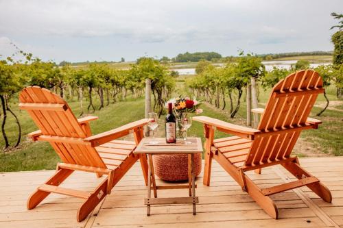 twee houten stoelen en een tafel met een fles wijn bij Cozy Wine Country Retreat at Painted Prairie in Currie