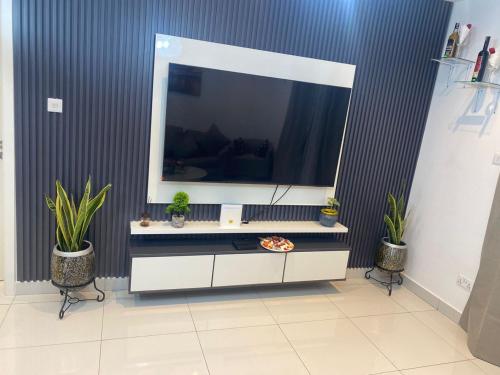 a living room with a tv and two potted plants at Waves luxury in Accra