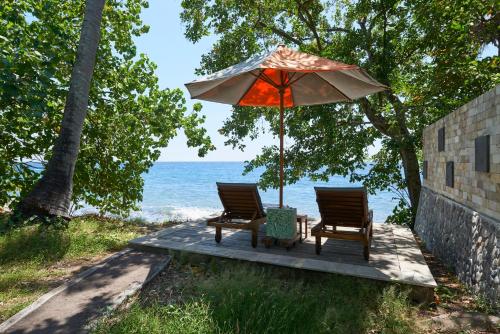 two chairs and an umbrella sitting on a wooden deck at Octopus Villas in Tejakula