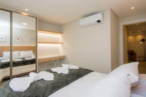 a bedroom with a large white bed and a mirror at Apartamento Luxo em Bento Gonçalves in Bento Gonçalves