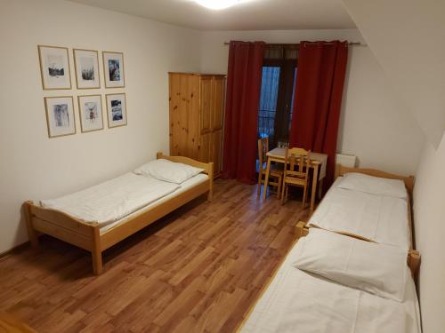 two beds in a room with a table and a dining room at Janicek in Ząb