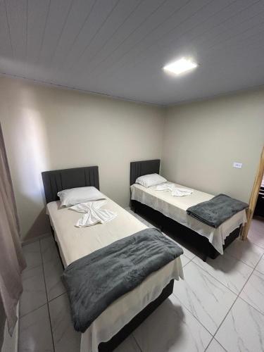 a room with two beds in a room at Pousada e Restaurante Zanella in Candói