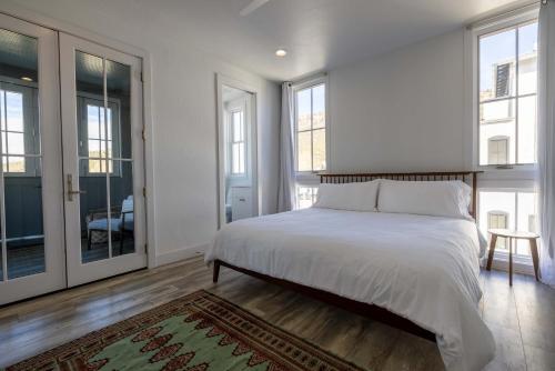 een slaapkamer met een bed met witte lakens en ramen bij The Jackalope Rooftop w Fire Pit & Epic Mountain Views in Buena Vista