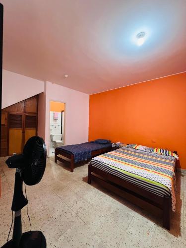 a bedroom with two beds and an orange wall at Espectacular y céntrico apartamento en el corazón de San Gil 1 in San Gil