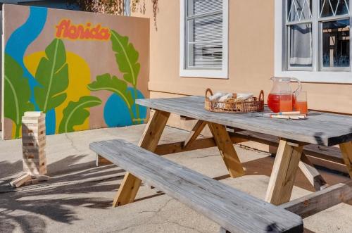 a picnic table with a basket of juice and a bench at The Cozy Jamozy in Panama City Beach