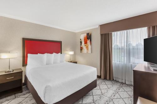 a hotel room with a large bed and a large window at Best Western Plus Rose City Suites in Welland