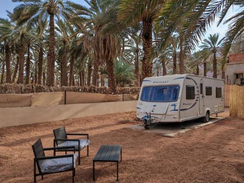 una furgoneta blanca aparcada delante de las palmeras en كرفان لحظة لقاء, en Al Ula