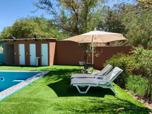 a backyard with a pool and an umbrella at Hostal Ribera de Quitor in San Pedro de Atacama
