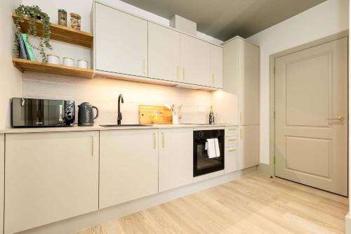 a kitchen with white cabinets and a black microwave at Apartment Nine Pelican House in Bournemouth