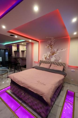 a bedroom with a large bed with pink lights at Apartman Flamingos in Rača