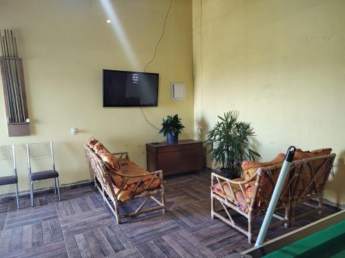 Cette chambre comprend deux chaises et une télévision à écran plat. dans l'établissement Pousada Da Montanha, à Extrema