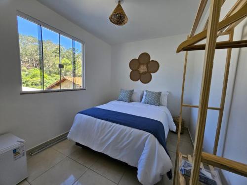 a bedroom with a bed and a large window at Villa Sol hospedaria in Paty do Alferes