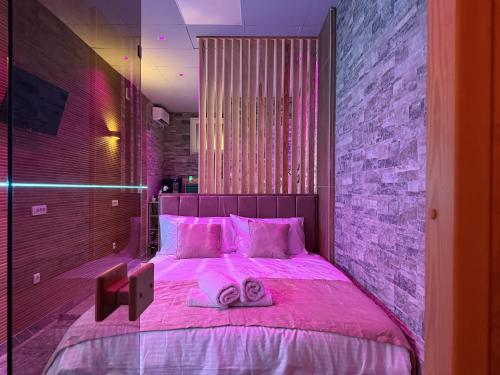 ein Schlafzimmer mit einem rosa Bett mit zwei Handtüchern darauf in der Unterkunft Dubai Spa Apartments - Jacuzzi, Sauna & Free Parking in Veternik