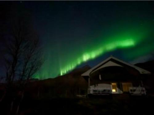 an aurora over a house with a building at Fjord & Flame in Tromsø
