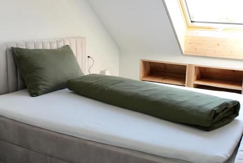 a bed with a green pillow on top of it at Fuchs at home in Kaltbrunn