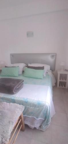 a bedroom with a large white bed with green pillows at Aguaribay pinamar in Pinamar