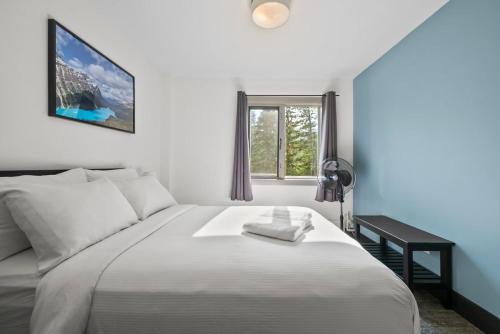 um quarto com uma cama branca com uma escrivaninha e uma janela em HI Lake Louise Alpine Centre - Hostel em Lake Louise