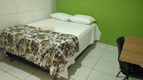 a bed in a green room with a table and a bedspread at Apartamento aconchegante in Marabá