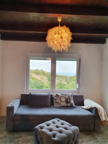 a living room with a couch and two windows at Pure nature lovely view house in Zaklopača