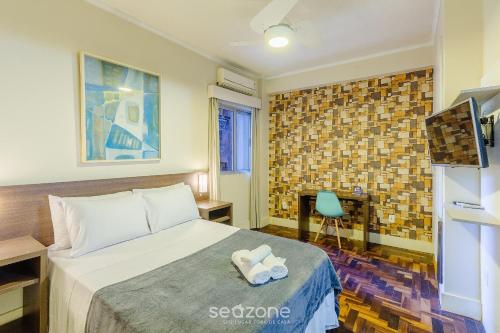 ein Hotelzimmer mit einem Bett und einem Fernseher in der Unterkunft Estúdios no Centro Histórico de Poa - ELSs in Porto Alegre