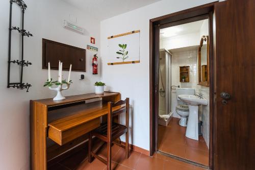 a bathroom with a sink and a toilet and a wooden table at Óbidos Priest Room in Óbidos