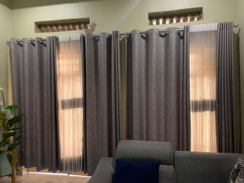 een woonkamer met grijze gordijnen en een bank bij Le Manoir in Kigali