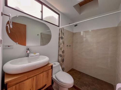 a bathroom with a sink and a toilet and a mirror at Finca Hotel Los Guayacanes in San JosÃ©