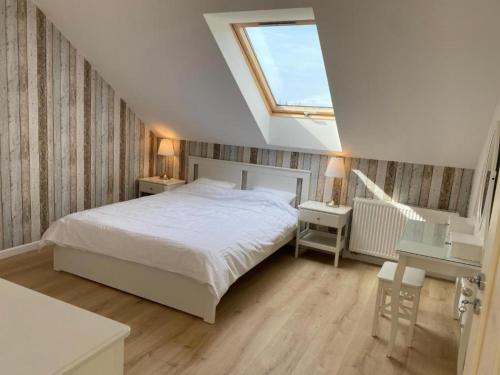 une chambre avec un lit blanc et une lucarne dans l'établissement Comfortable, 2-level holiday apartment, à Grzybowo
